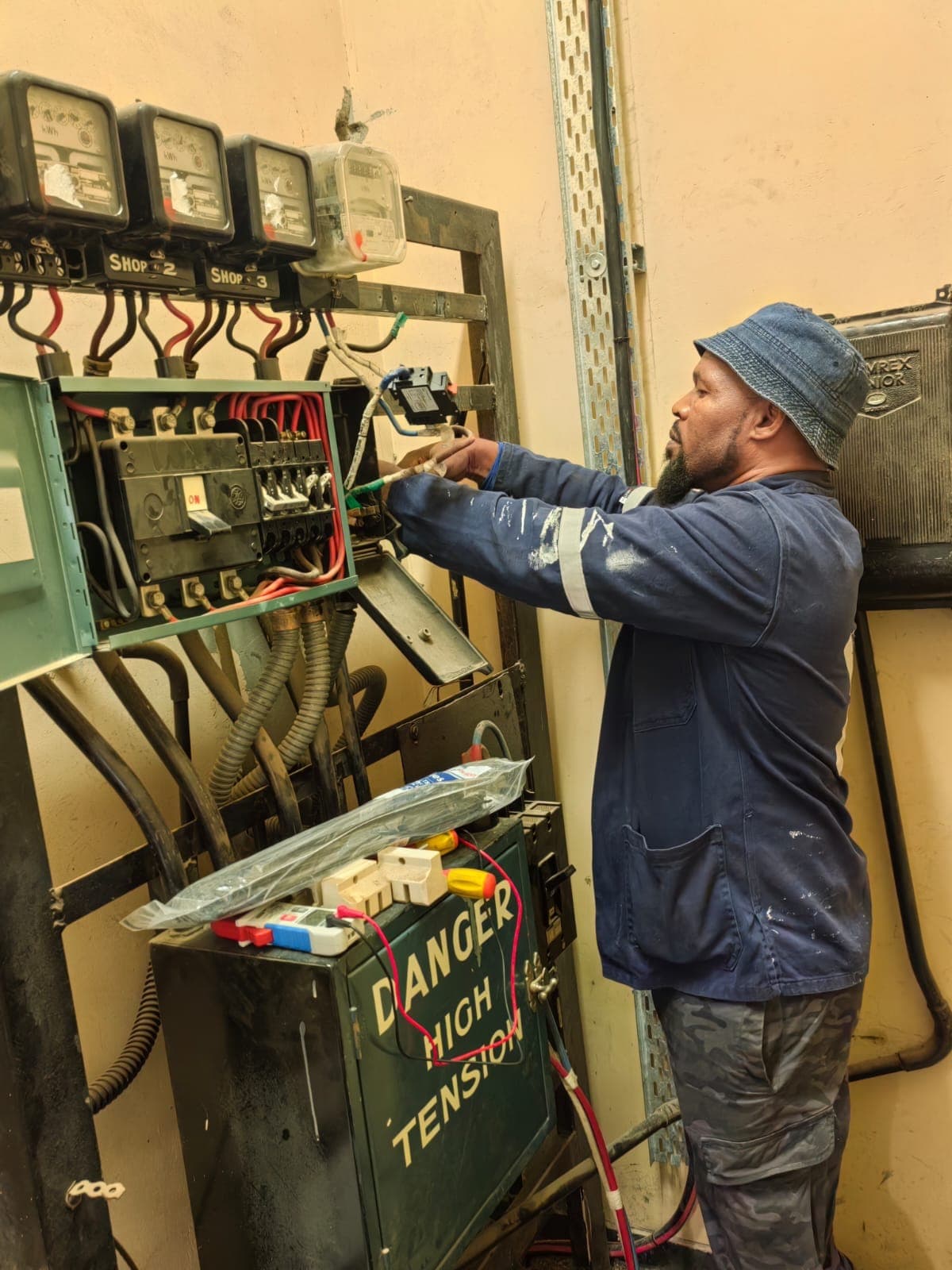 Mthombeni technician working on a shop meter board in a commercial building