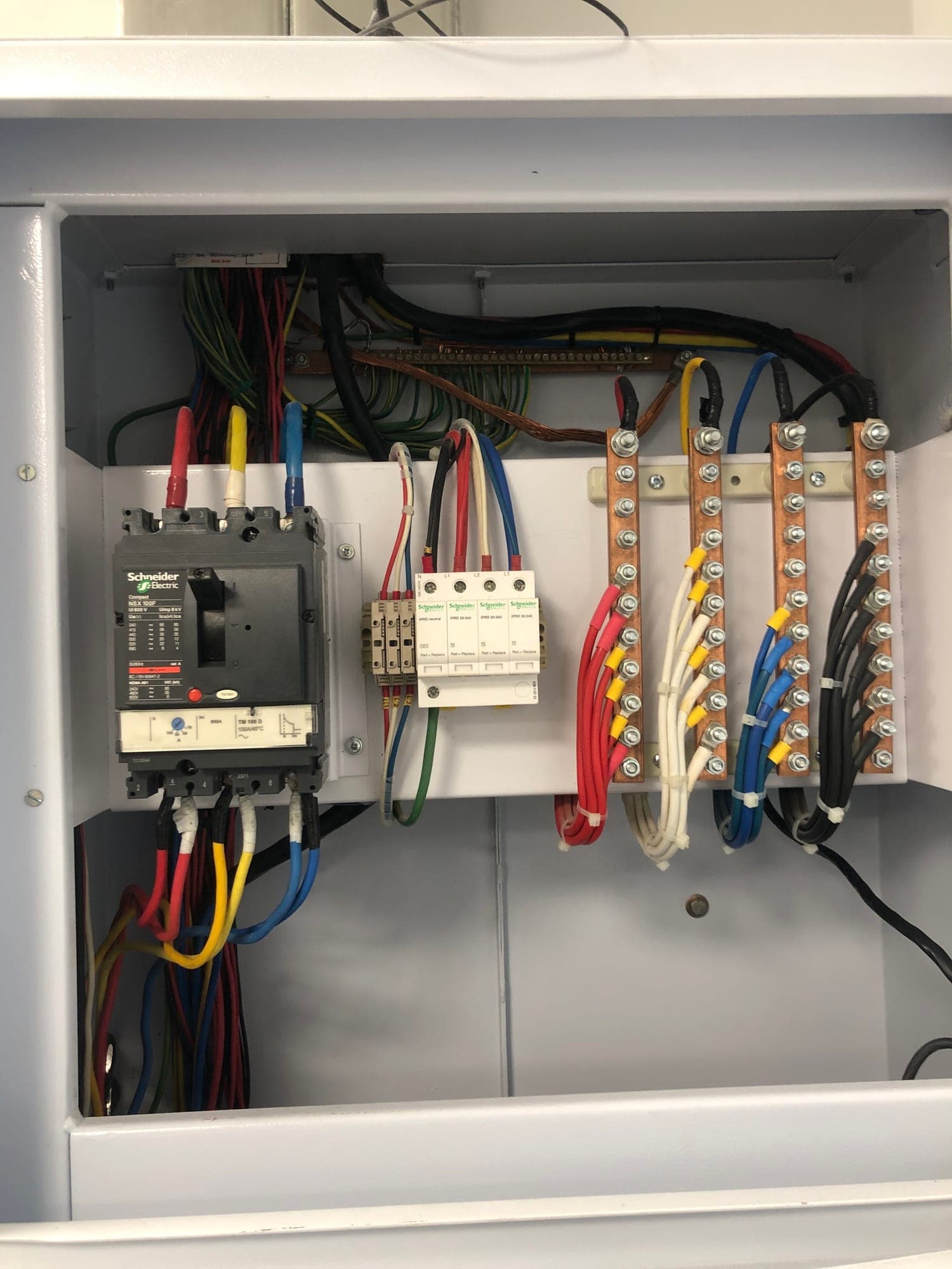 Three-phase distribution board with a Schneider main breaker, surge protection and neatly terminated copper busbars